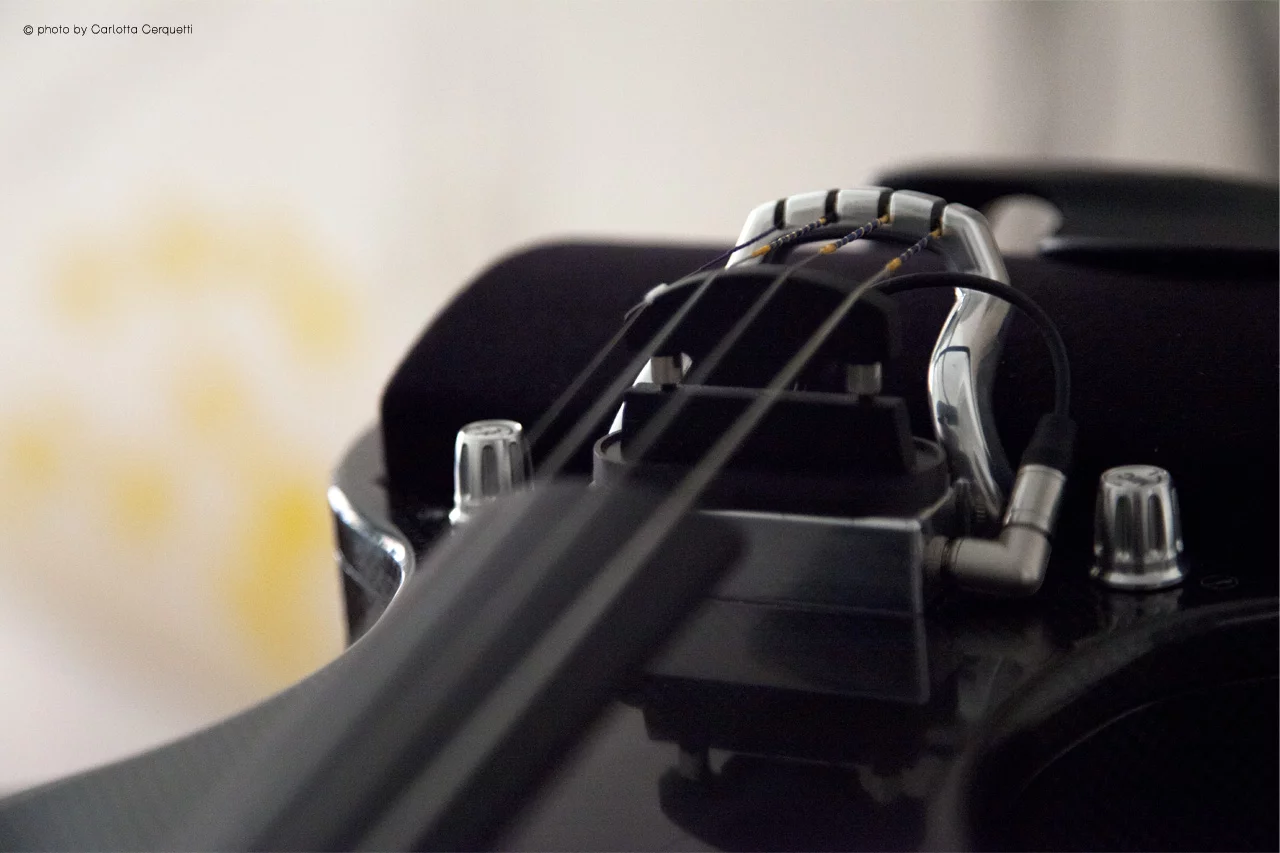 String vibrations are picked up by a piezoelectric transducer or magnetic pickup