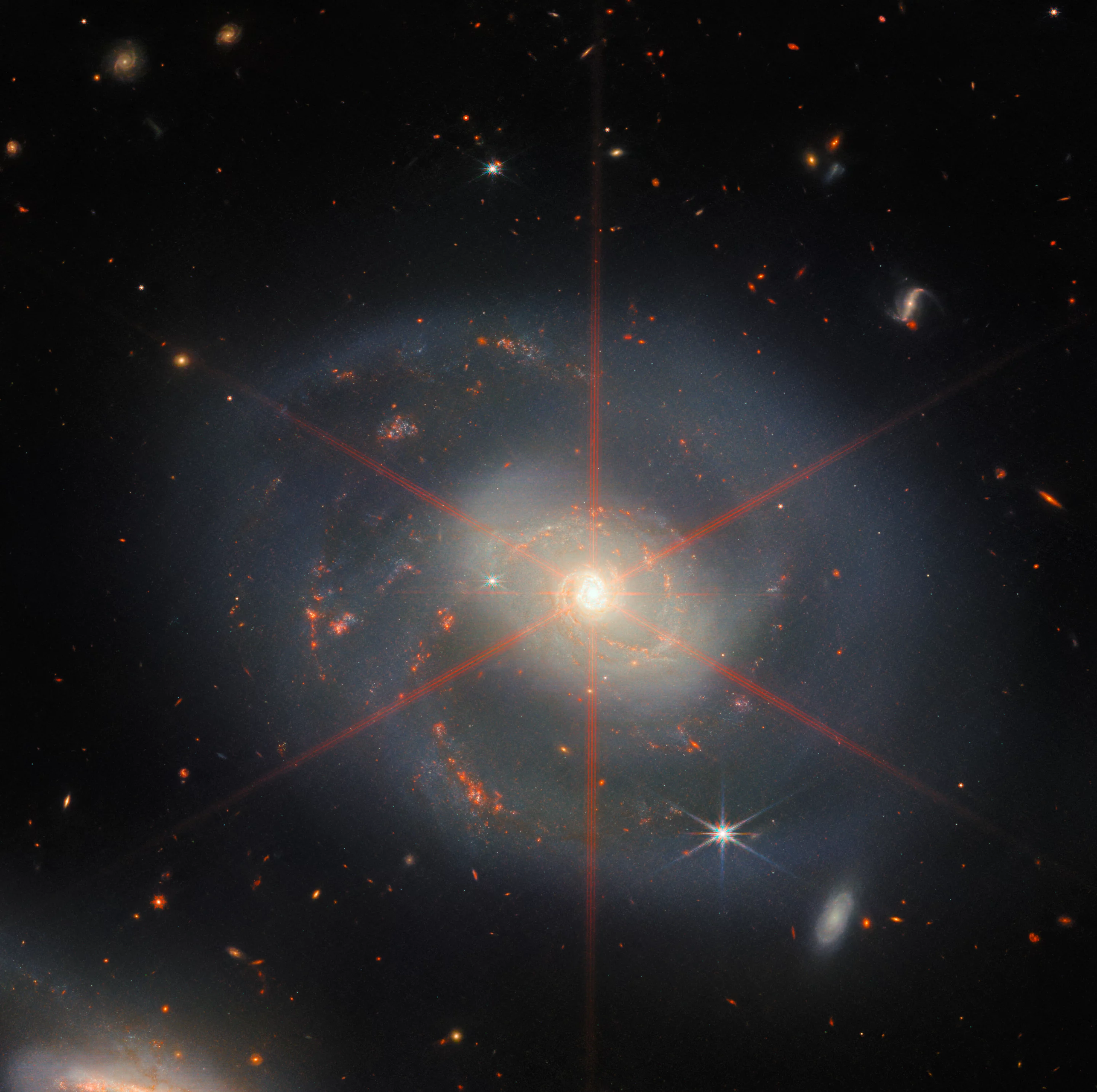 Webb's most recent image, released just before Christmas 2022, shows the galaxy NGC 7469 looking a lot like a holiday wreath. The red spikes are artifacts on the image and not really present in the galaxy
