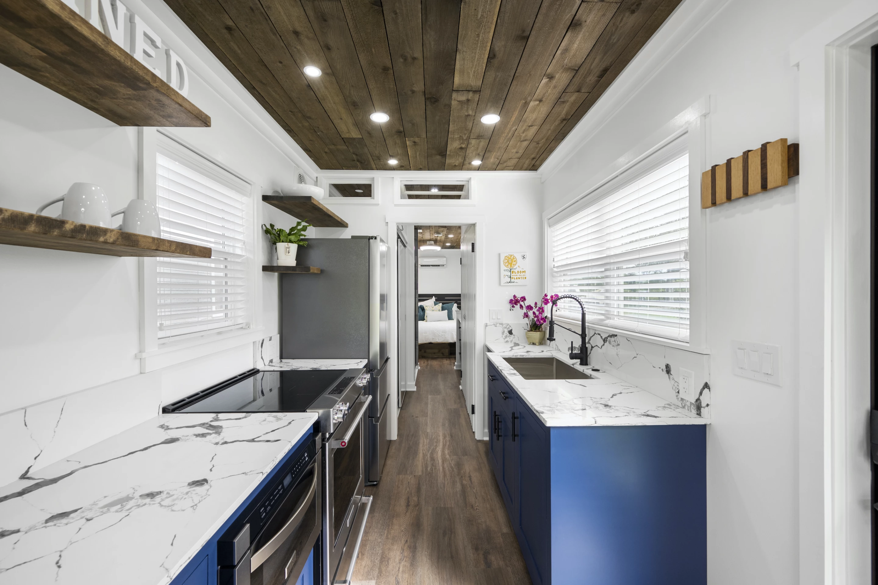 The Rising Sun's kitchen is well-stocked for a container-based tiny house and includes a microwave, oven, fridge/freezer, sink, cabinetry, and shelving