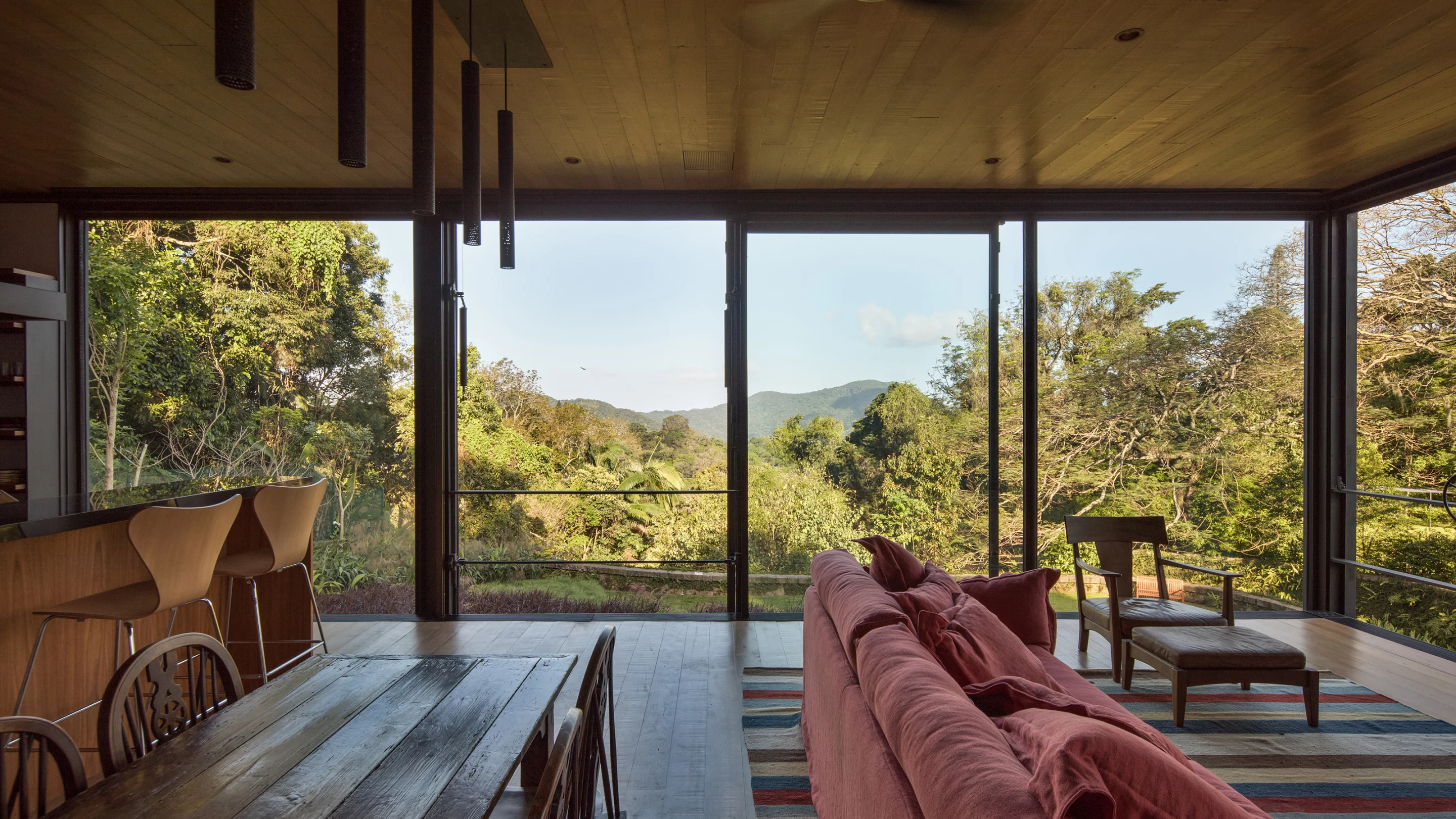 Rio House is located on the border of a national park and takes the form of a steel and glass box rising into the rainforest canopy. Its open living areas help frame the view and promote natural ventilation inside
