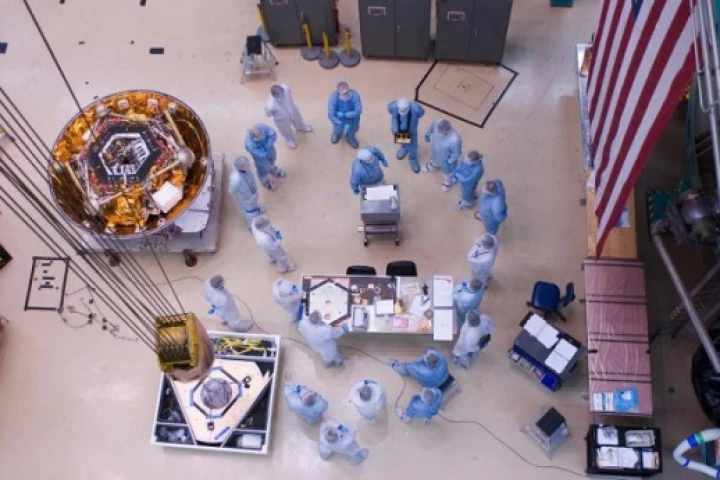 Spacecraft specialists huddle to discuss the critical lift of NASA’s Phoenix Mars Lander into a thermal vacuum chamber. In December 2006, the spacecraft was in a cruse configuration prior to going into environmental testing at a Lockheed Martin Space Syst