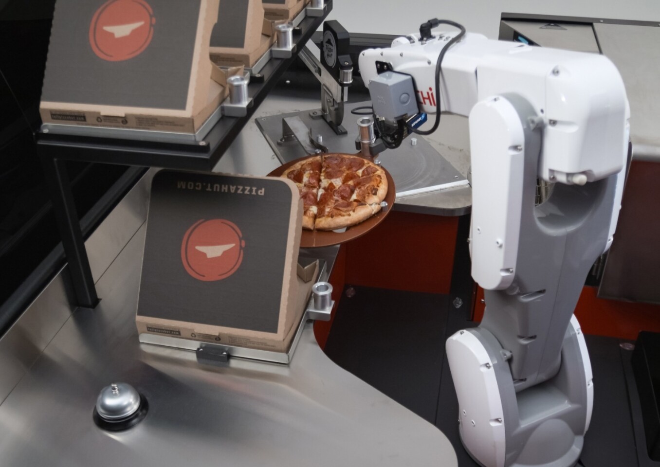 The finished, sliced pizza is boxed and delivered to a customer by a robotic arm