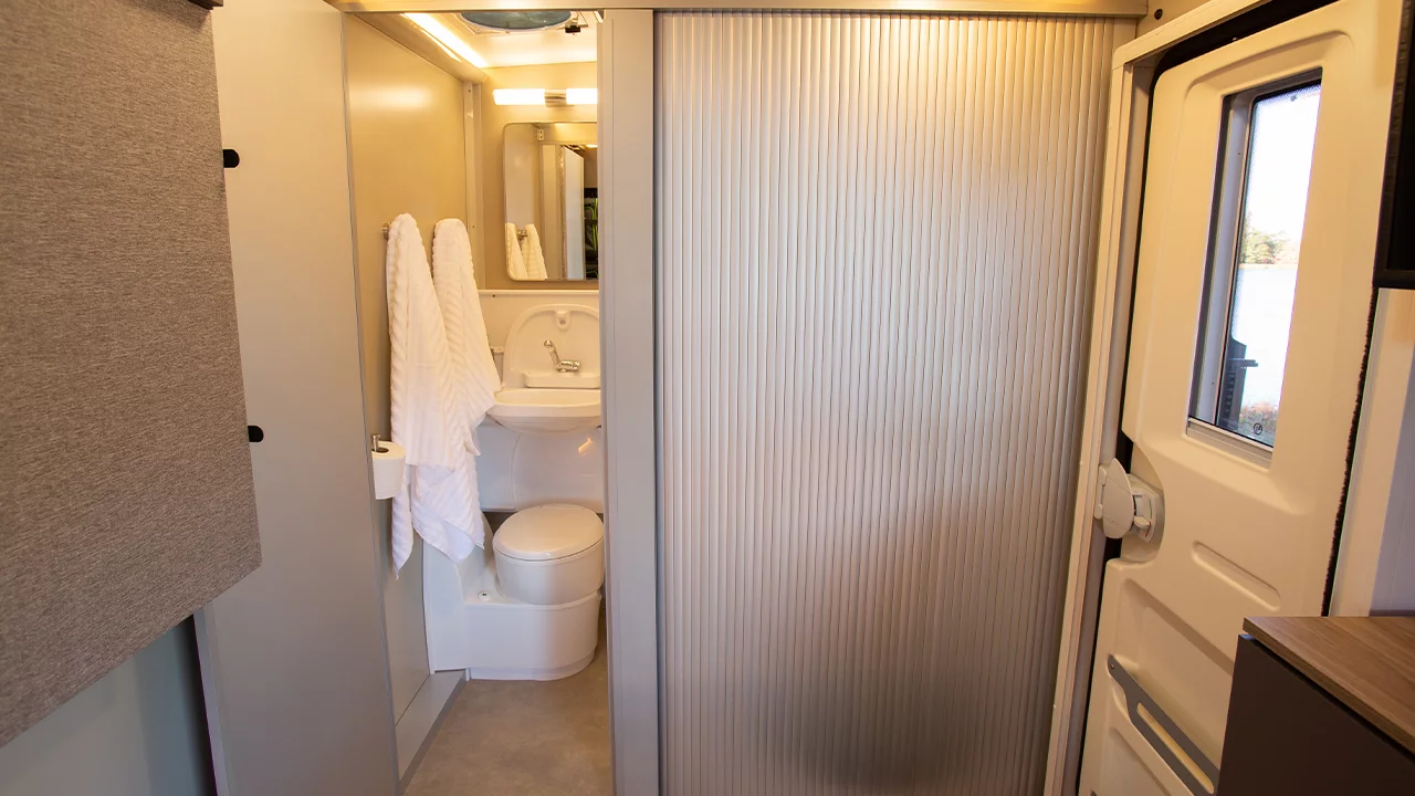 An accordion door separates the shower area from the rear of the trailer
