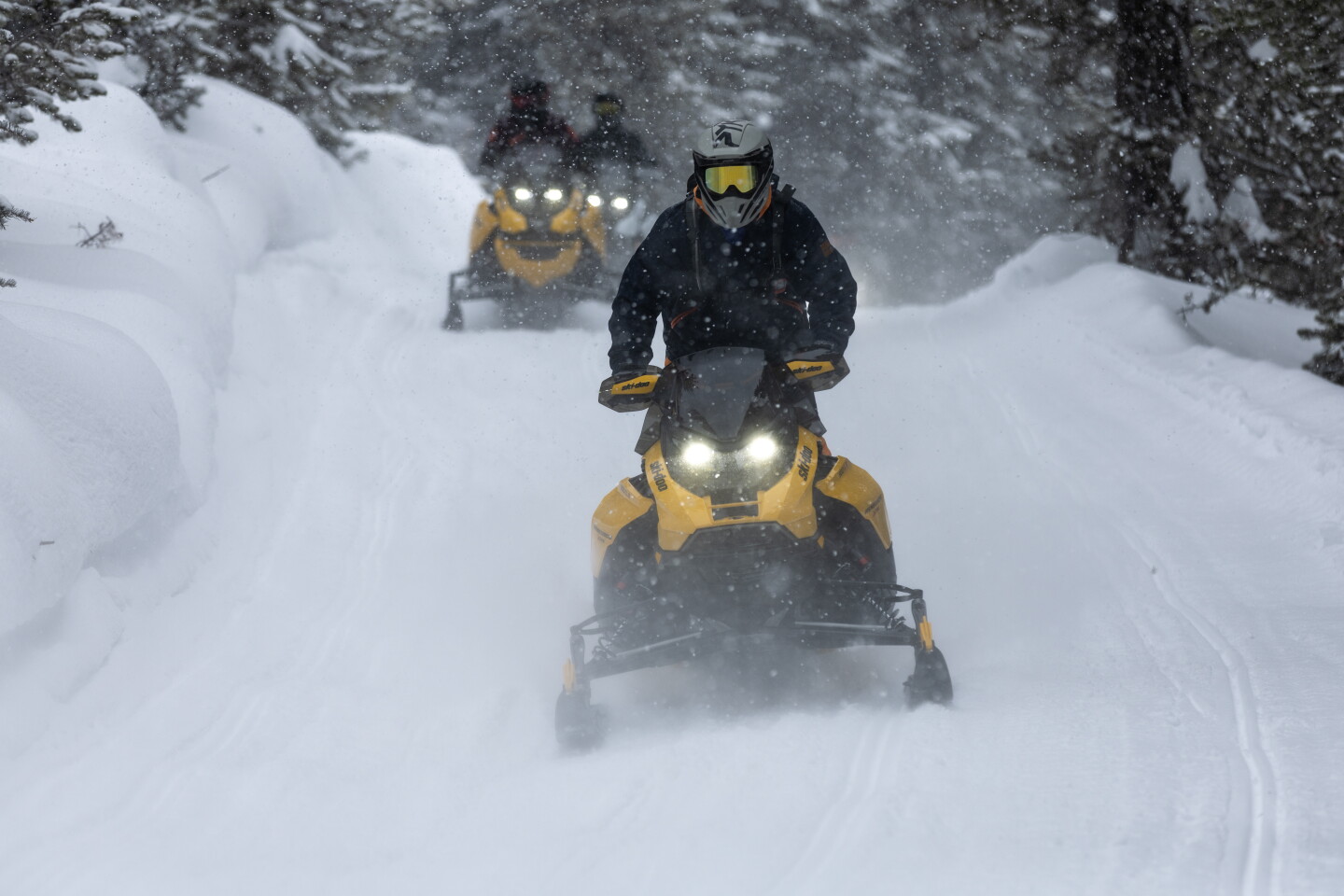 Standing to absorb the bumps, the author skis through the wilderness on a Ski-doo snowmobile