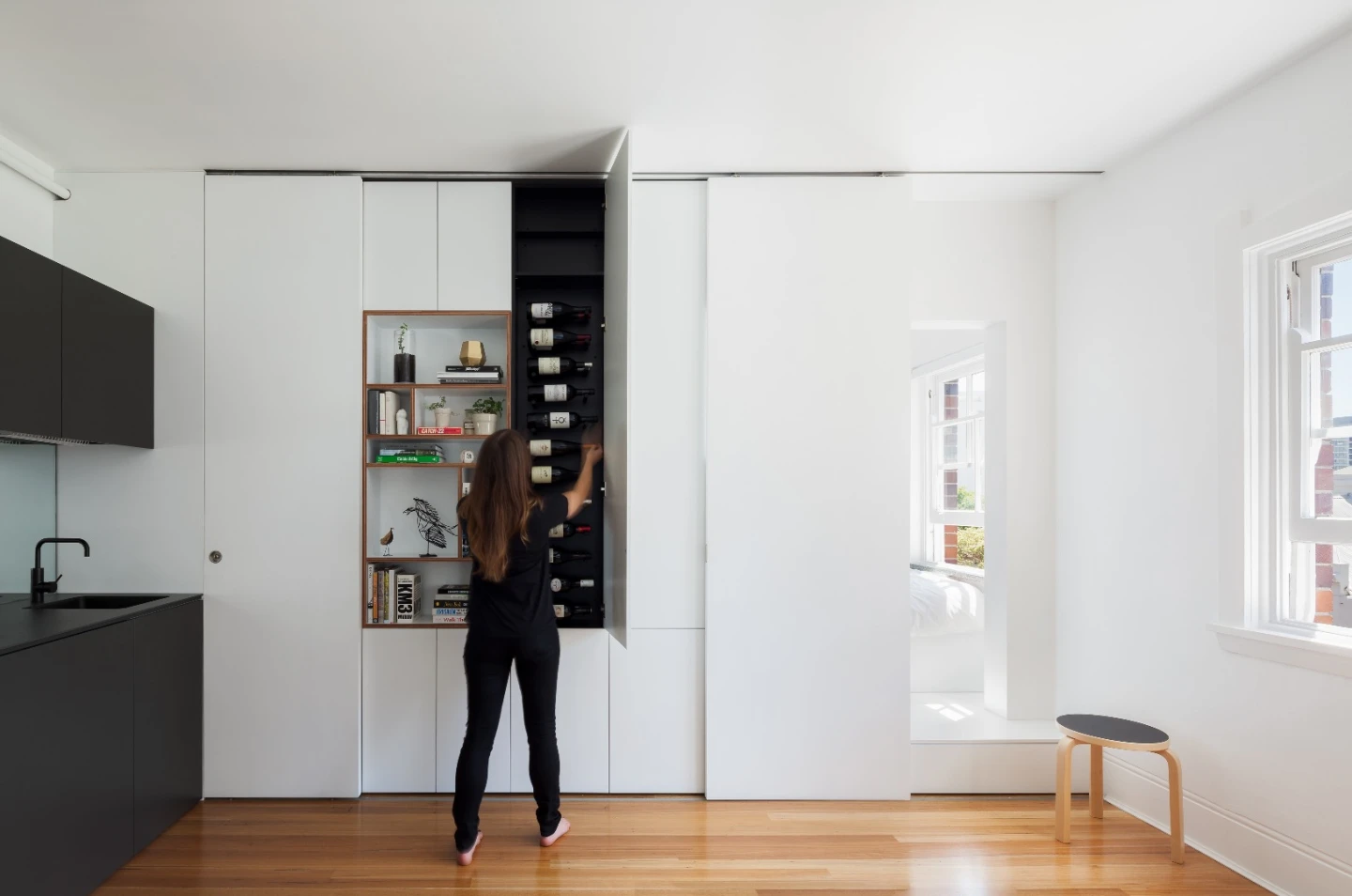 The multi-purpose wall conceals the entrance to the bedroom, along with a flat screen TV, bookshelf, a vertical wine rack and a fold-down desk