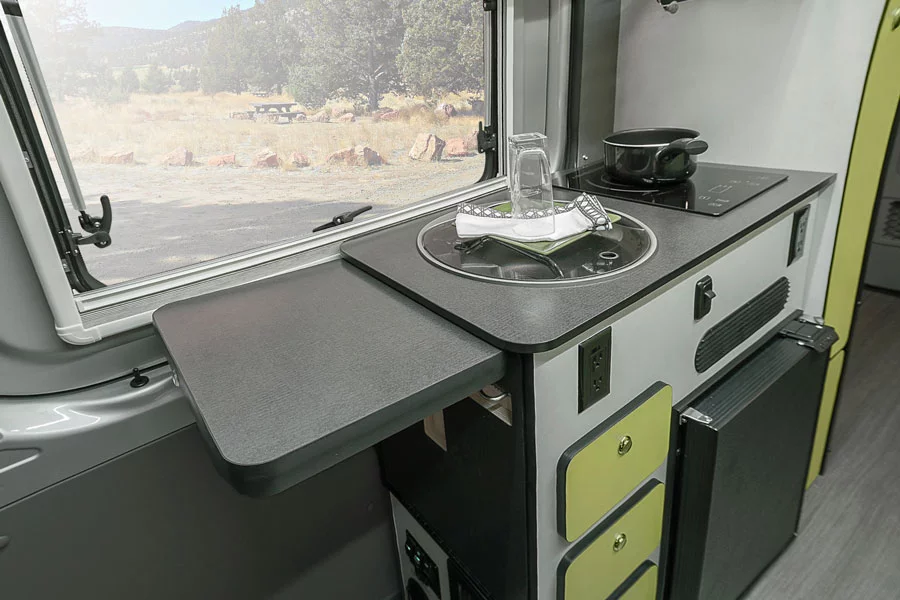 The kitchen has an electric single-burner and sink, both with glass covers