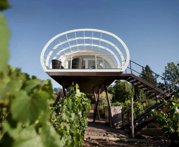 The unit is a cocoon shaped cabin that is supported by several irregularly placed steel columns.