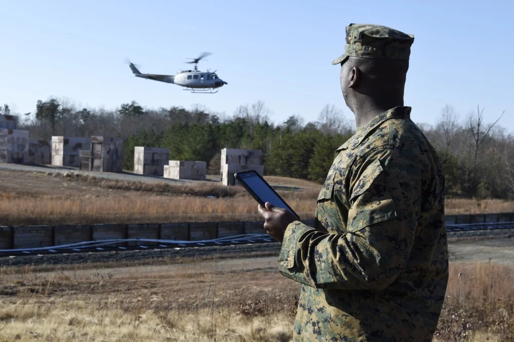 Sgt. Dionte Jones watches as a UH-1 Huey equipped with AACUS autonomy kit departs the landing zone following a resupply mission he requested using a handheld tablet