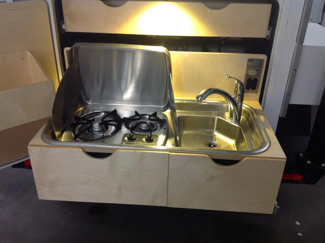 The Turtleback Trailer kitchen has a stainless steel two-burner stove and sink