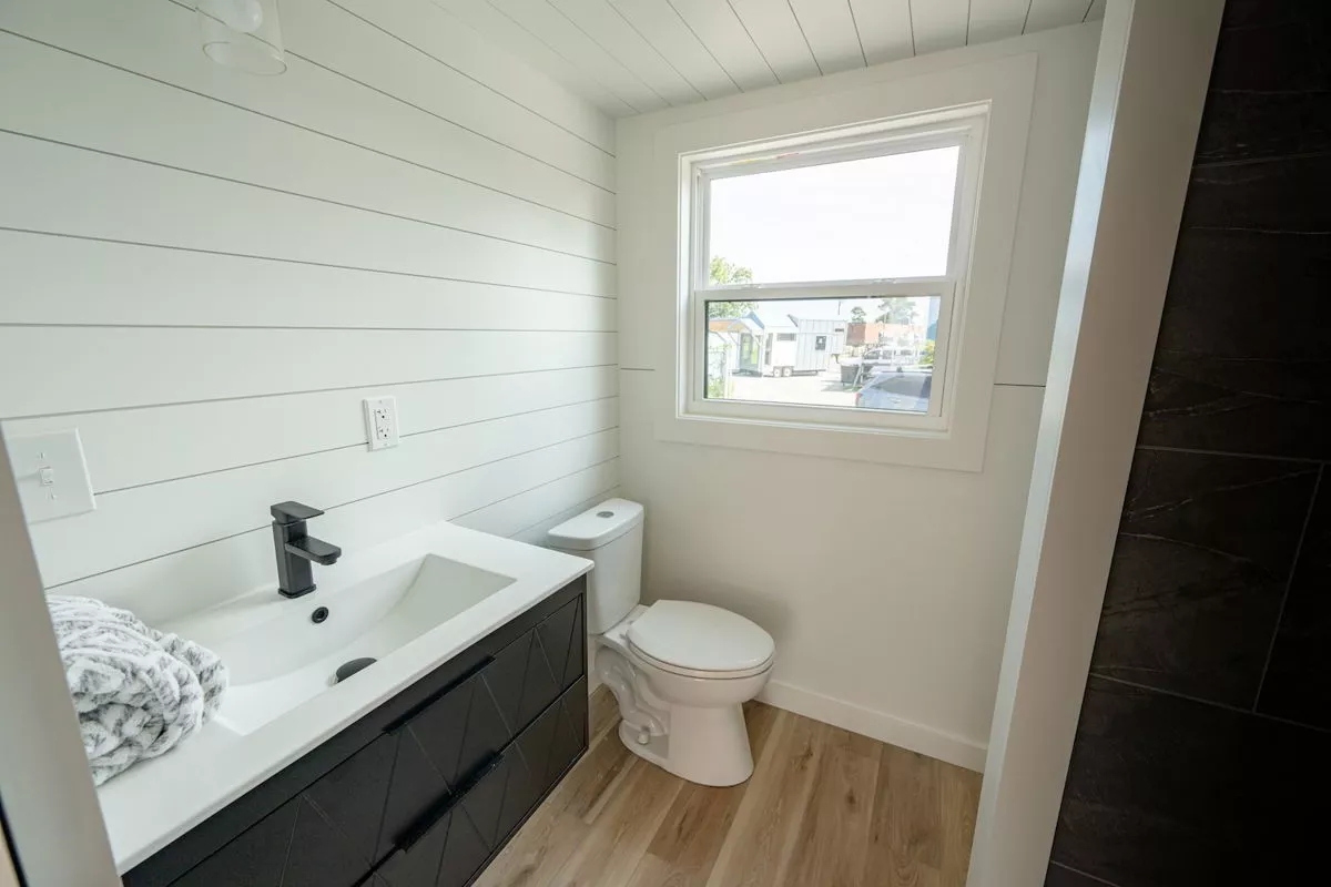 The 28' Model Tiny's bathroom includes a wall-mounted sink and a flushing toilet