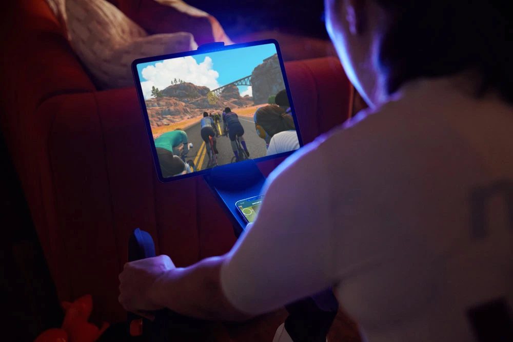 Dual pushbutton control pads on the drop handlebars allow users to perform Zwift gaming actions such as giving RideOns (cheering other players on) or activating earned power boosts known as PowerUps