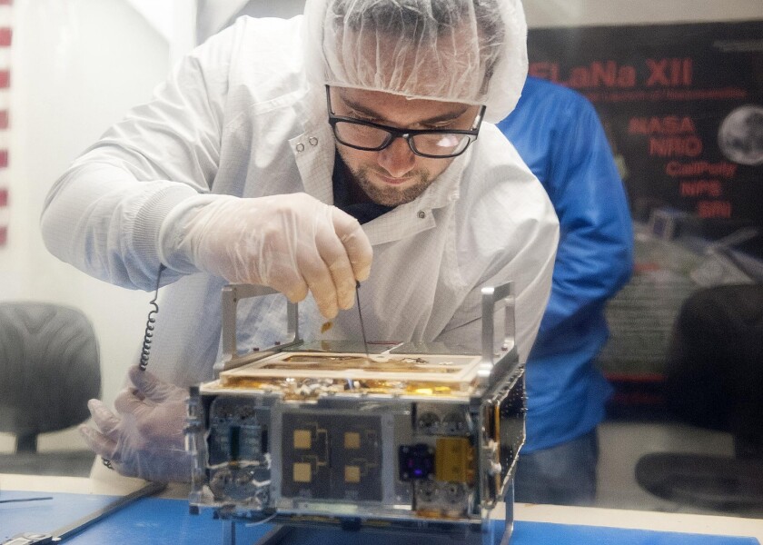 Joel Steinkraus, MarCO lead mechanical engineer from JPL, makes an adjustment on the CubeSat prior to integration in a deployment box as seen inside the cleanroom lab at Cal Poly San Luis Obispo