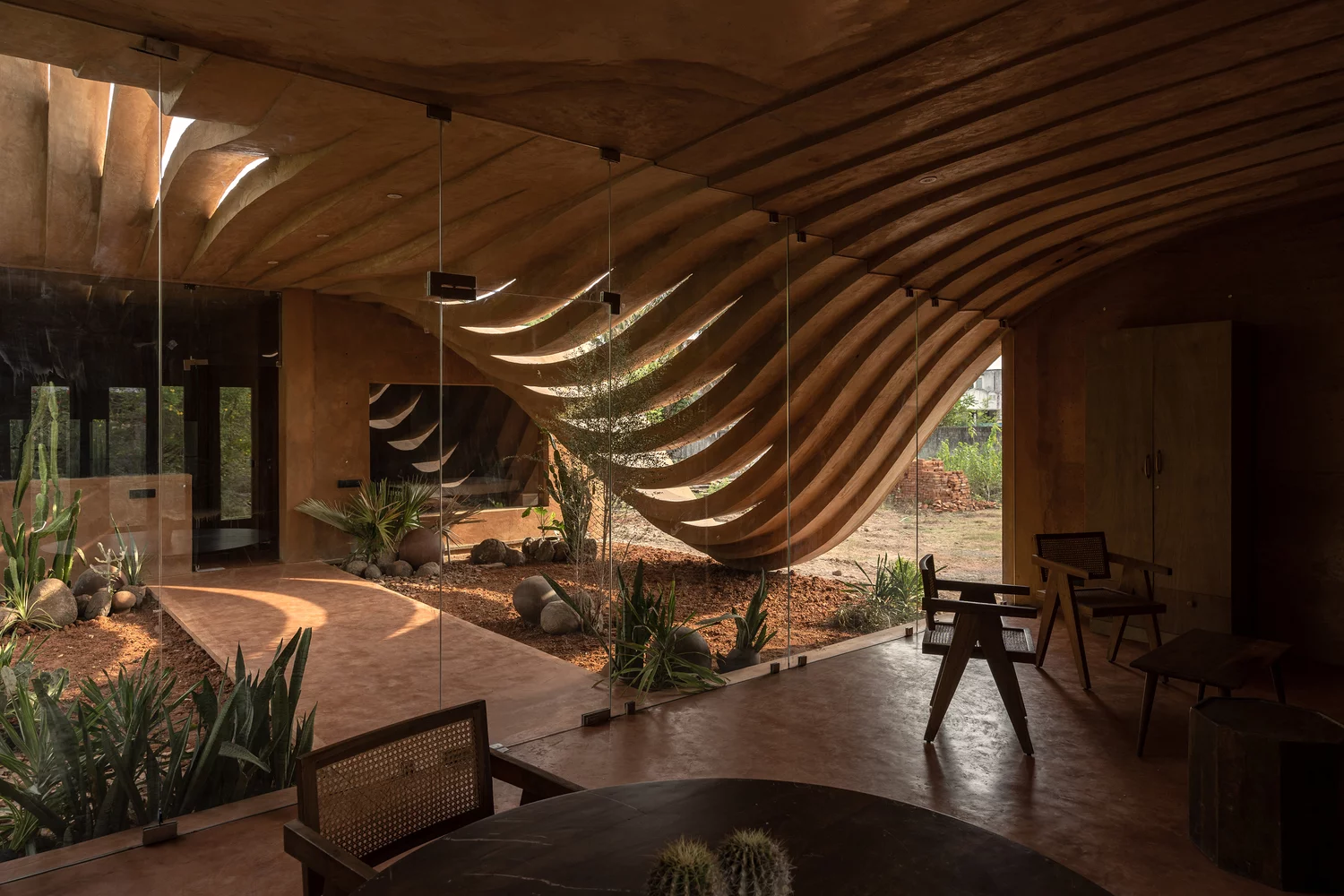 A curved, perforated wall shields the home from the western sun while playing with the sunlight