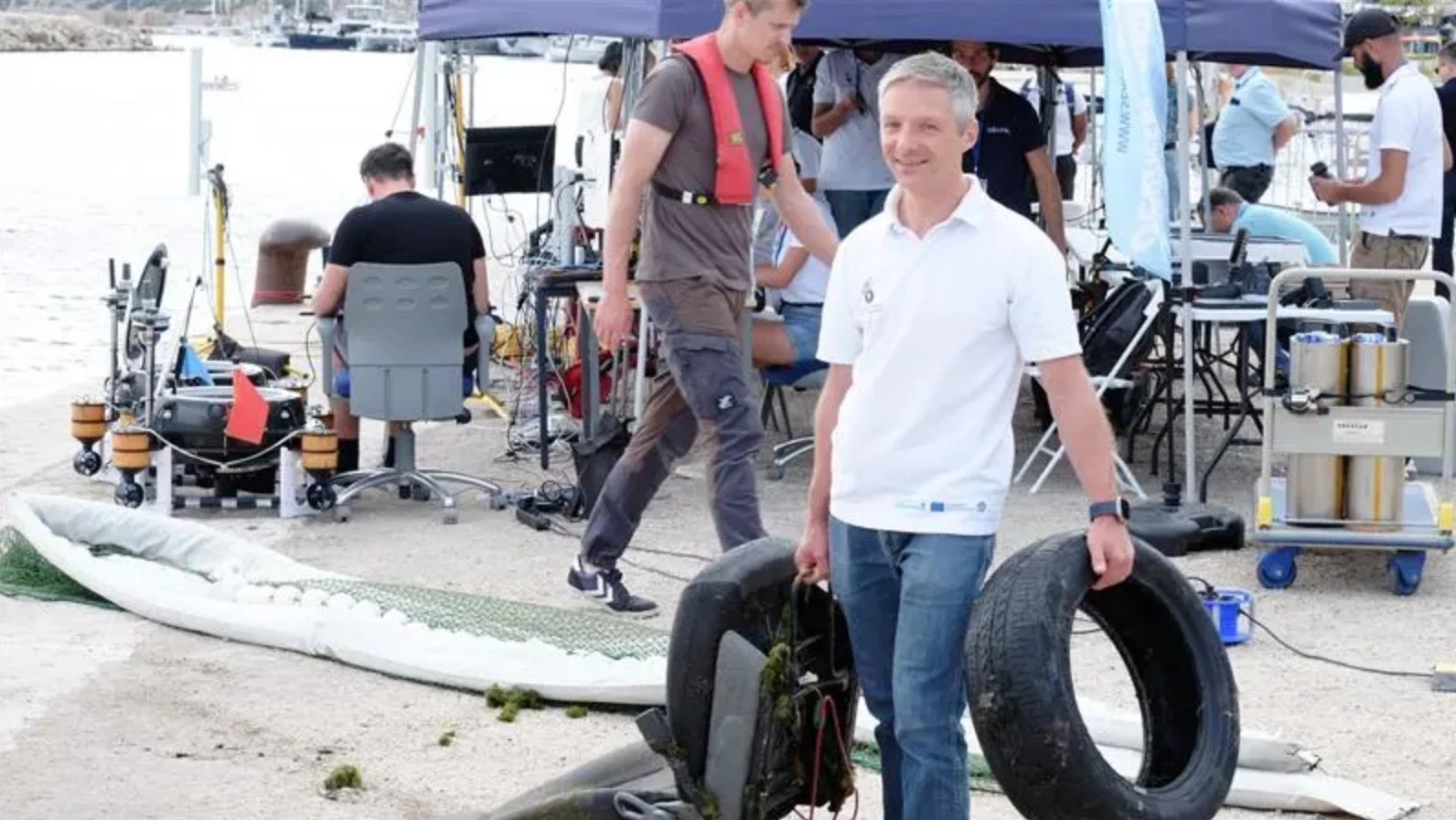 The team's Dr. Stefan Sosnowski hefts a car seat and tire recovered from the port of Marseille by the autonomous trash collector