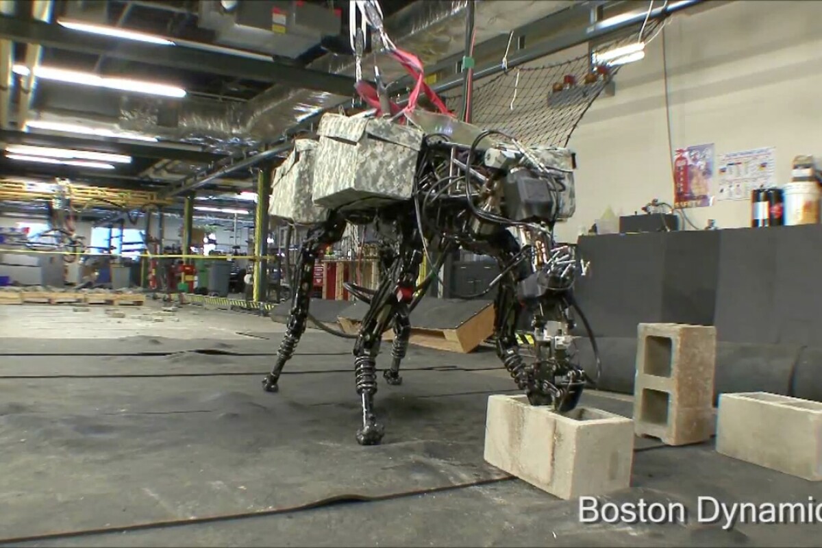 Boston Dynamics' quadruped robot BigDog grabs a cinder block from the floor using its new arm attachment