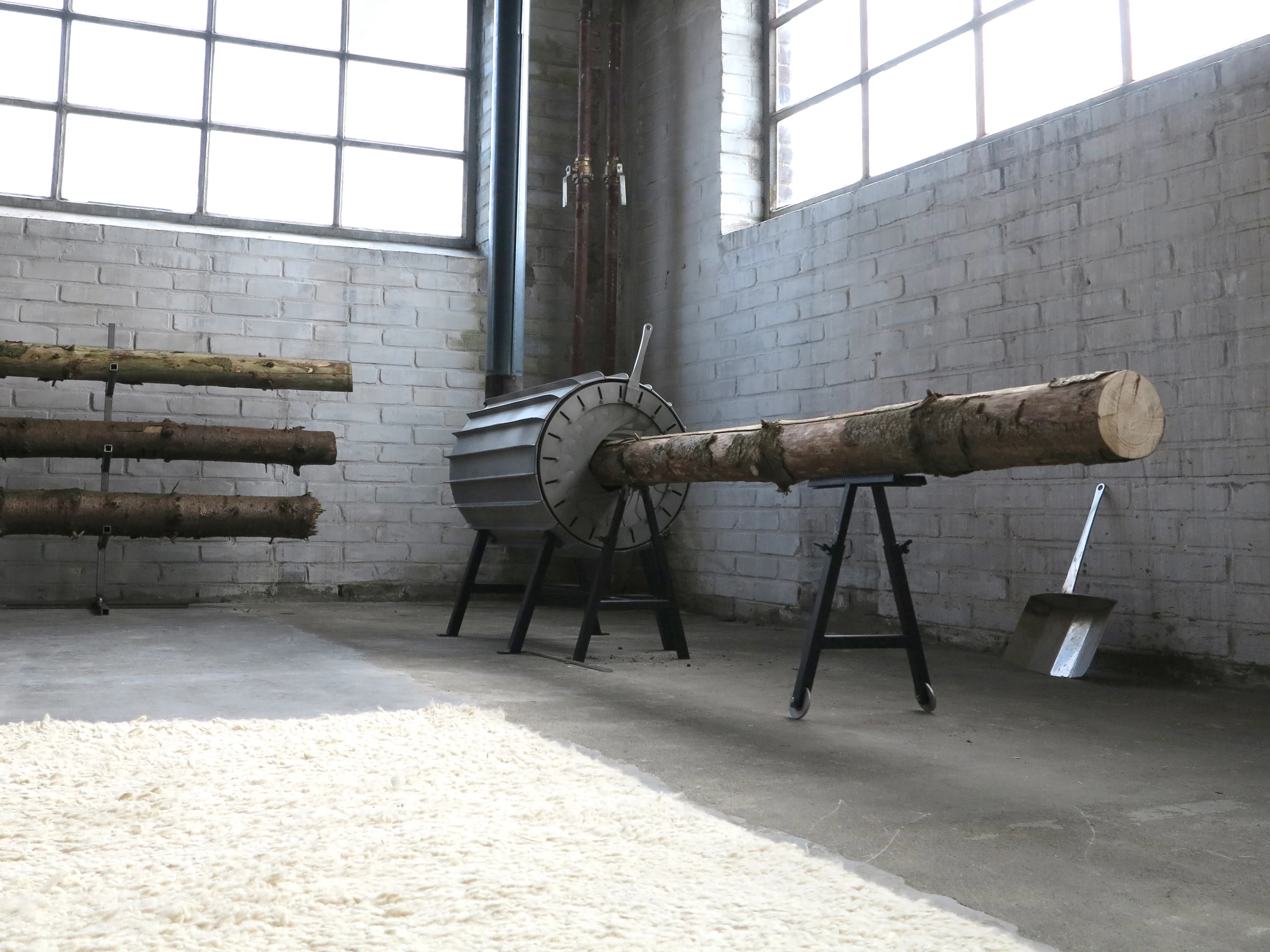 Users start by placing a log on the adjustable-height support stand, then pushing it into the cylindrical stove