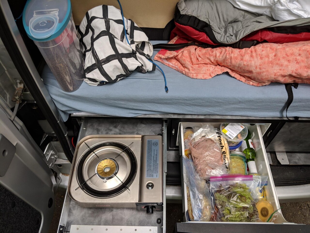 The compact kitchen includes a single-burner stove, small fridge and storage