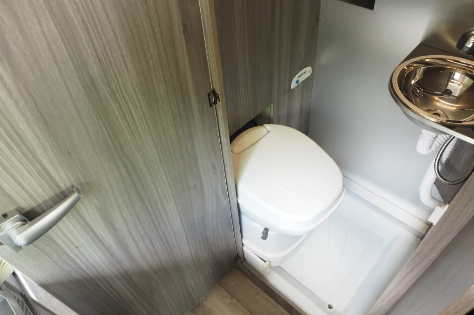 Just behind the rear two-seat bench, the slim bathroom includes a toilet and sink with shower faucet