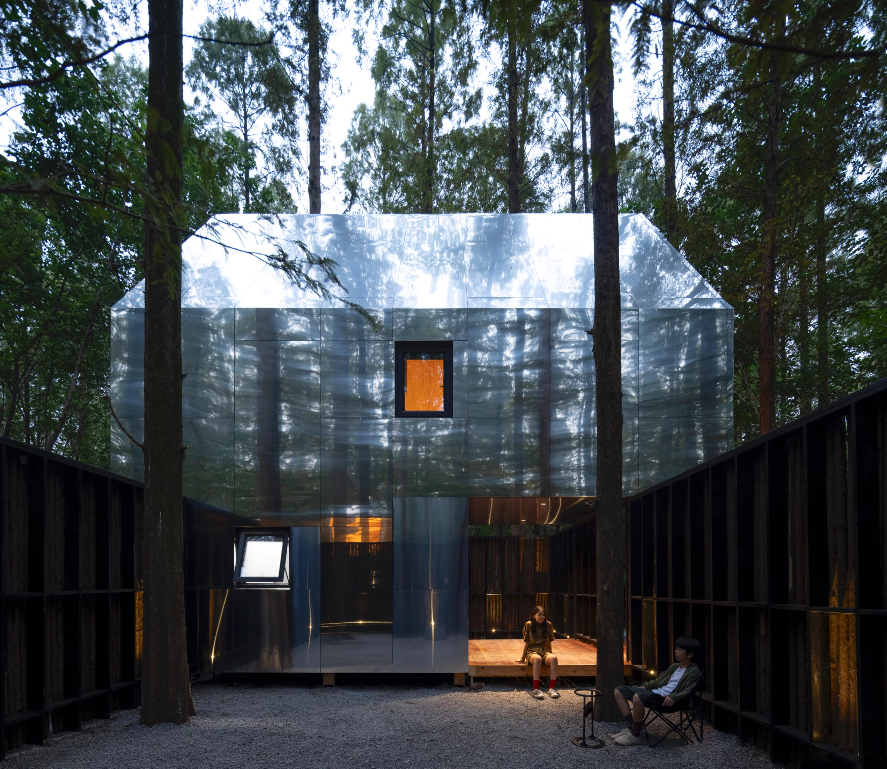 The cabin facade reflects the surrounding forest like a mirror