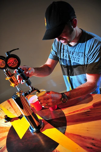The Beer Bike is a custom-built cargo bicycle that features two beer kegs, a wooden bar with two serving taps, space for pizza boxes, and a solar-powered boom box