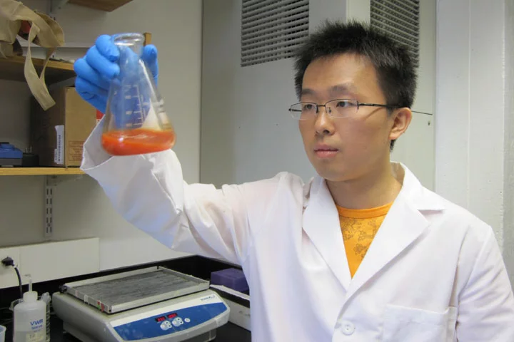 Brown University's Qi Wang swirls a solution of selenium nanoparticles