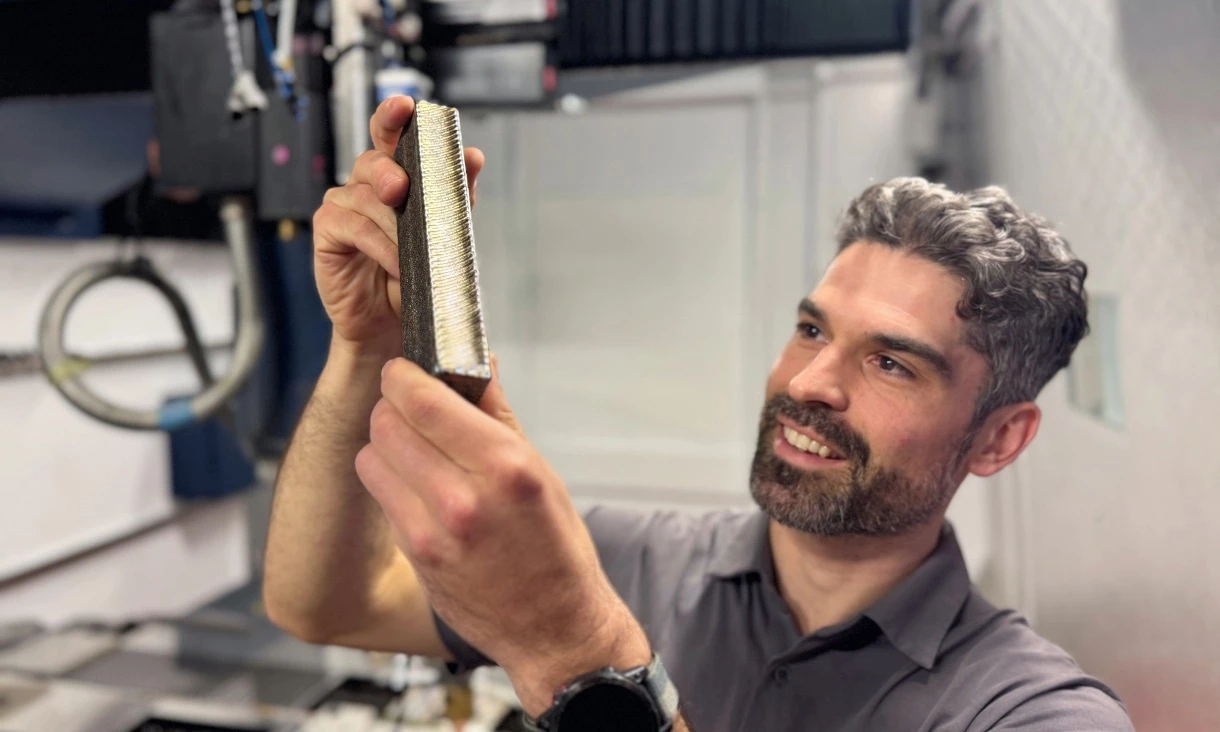 Study lead author Ryan Brooke inspects a sample of the new titanium alloy that's 30% cheaper to produce than standard titanium