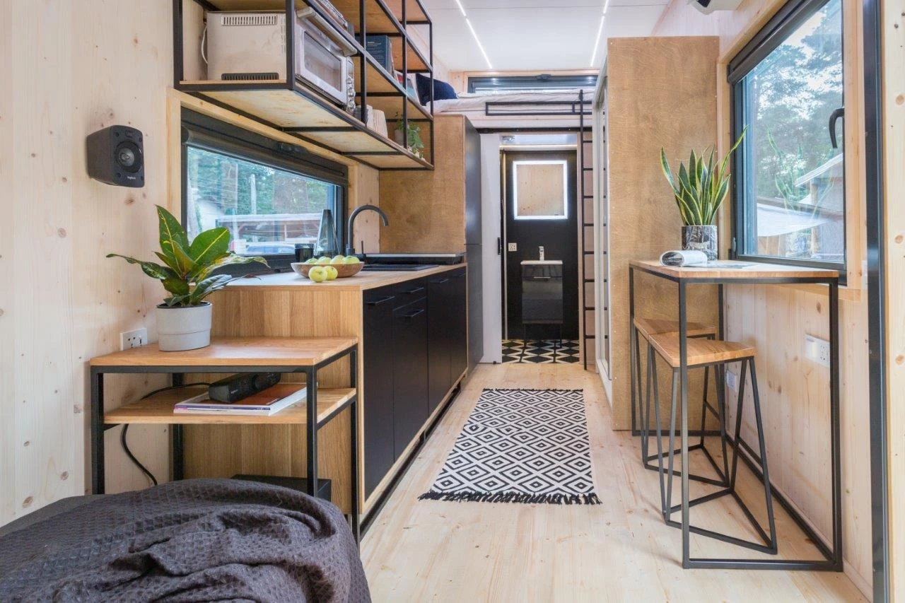 The Dark Vader's kitchen includes a breakfast bar seating area for two, a microwave, a sink, an induction cooktop, and a fridge/freezer