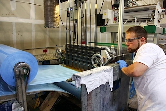 A North Sails employee coats fibers with thermoset adhesive