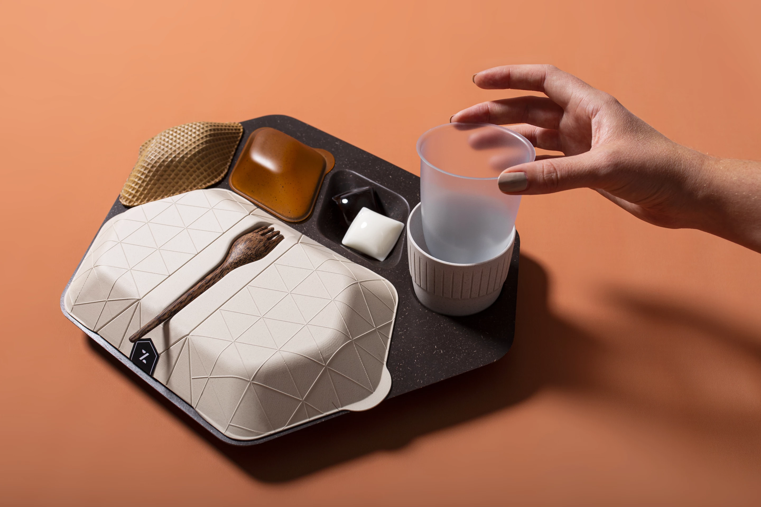 The in-flight tray concept includes a reusable tray made from coffee ground and husks mixed with lignin binder