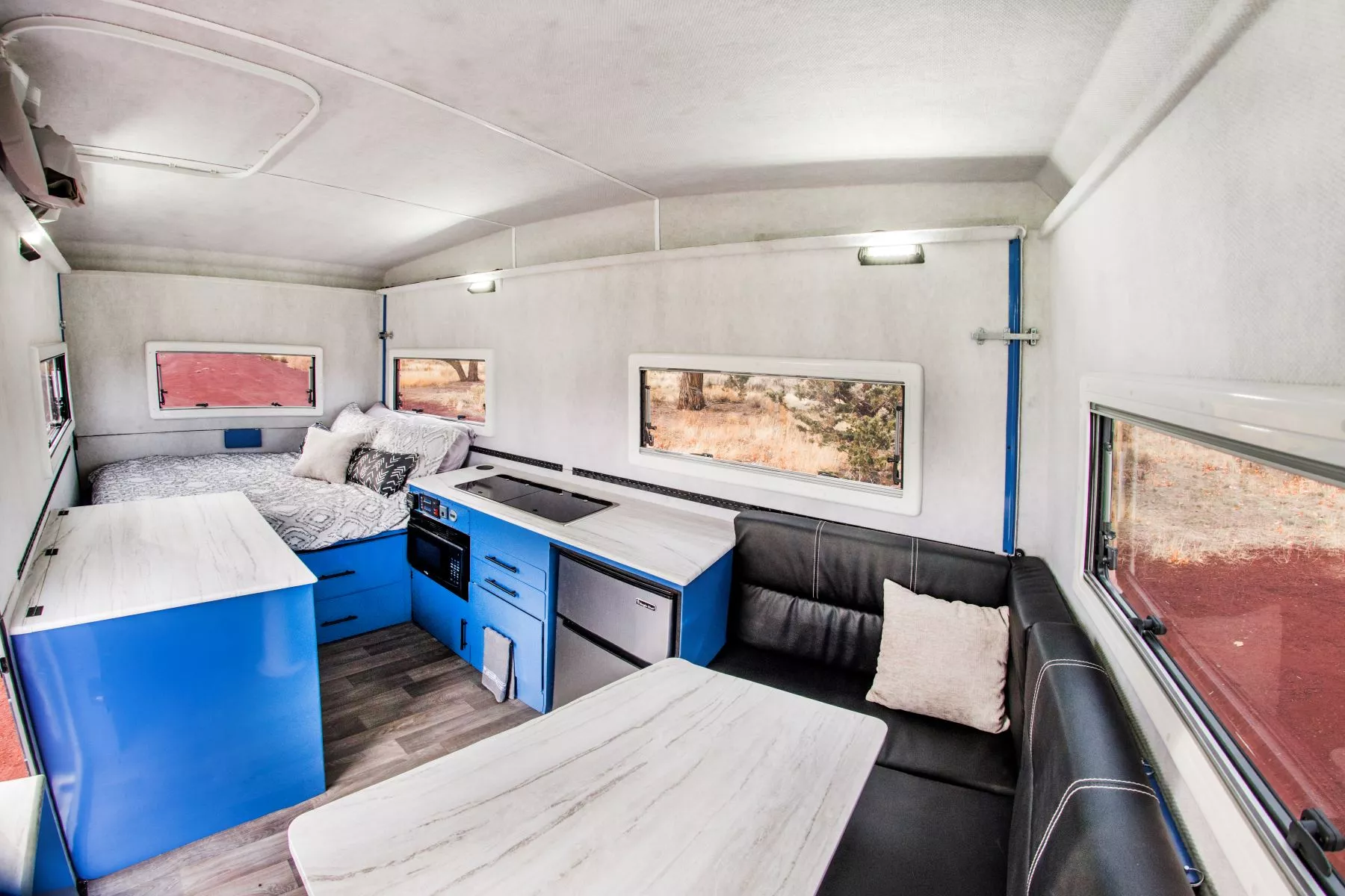 The Cube Series pop-up trailer interior includes sleeping space for four, a collapsible wet bath (front left), a rear master bed, a full kitchen and a dining lounge with wraparound sofa