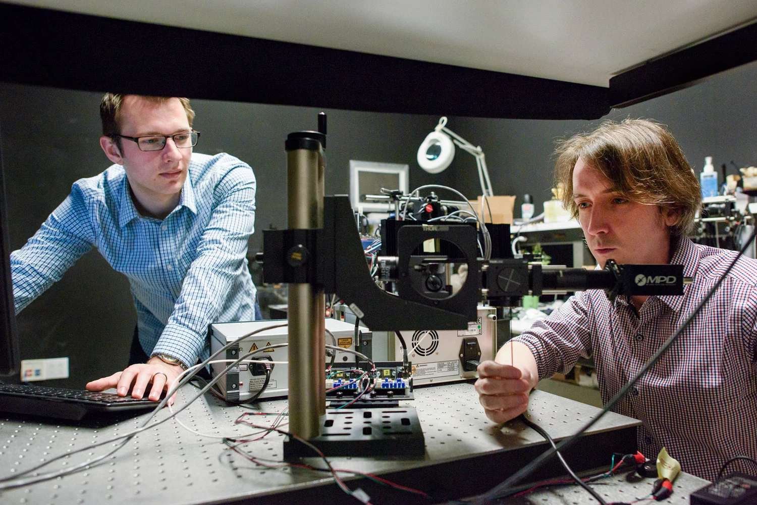 Stanford researchers David Lindell (left) and Matt O’Toole work on a laser-based system that can detect hidden objects around corners