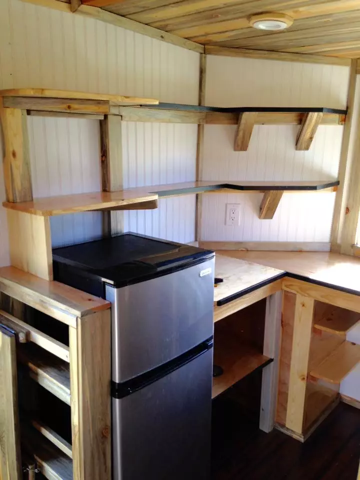 The kitchen area includes fridge, sink, two-burner cooktop, convection oven and on-demand water heater