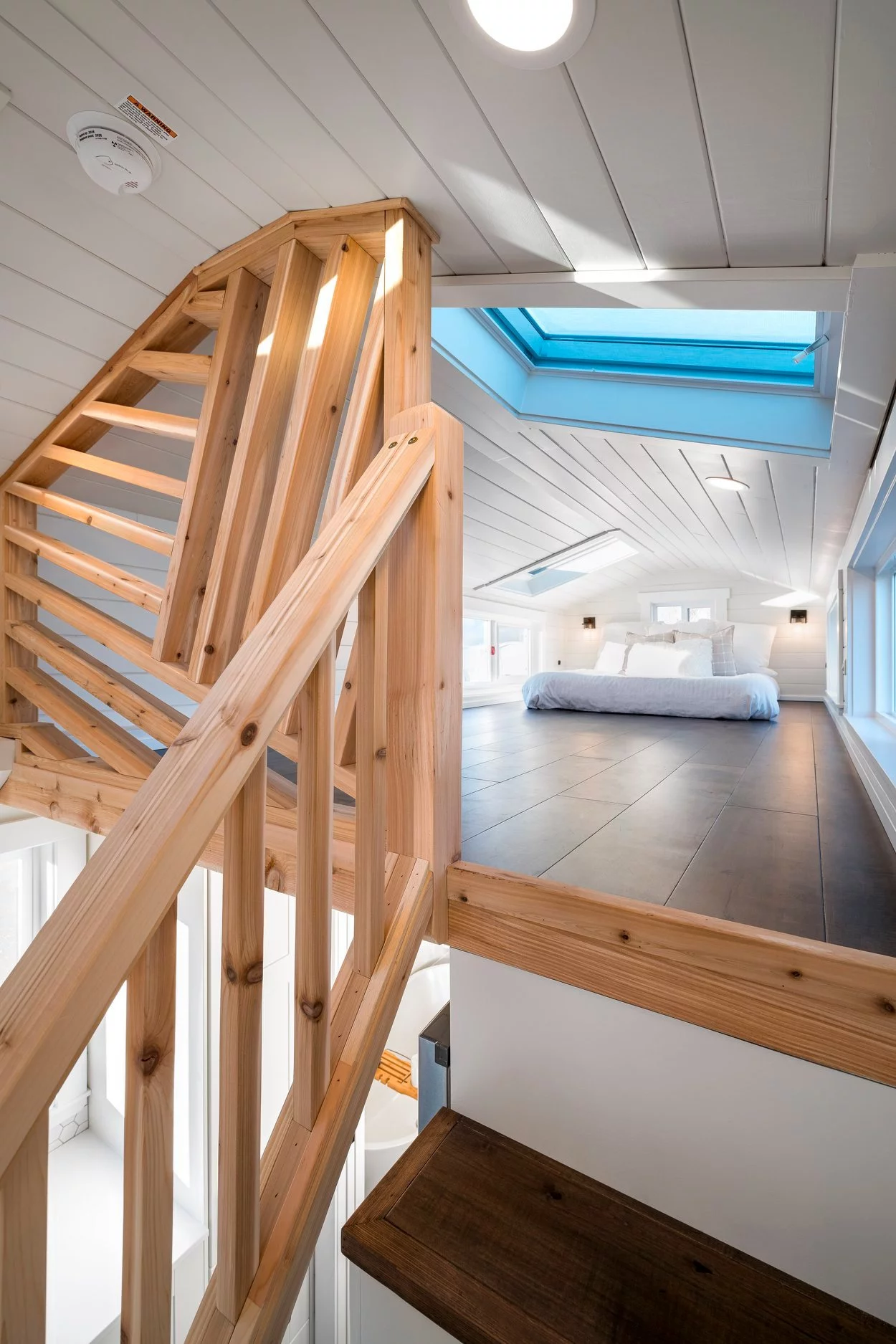 The 34ft Eco-Friendly Tiny House RV's main bedroom is reached by storage-integrated staircase and is topped by a skylight