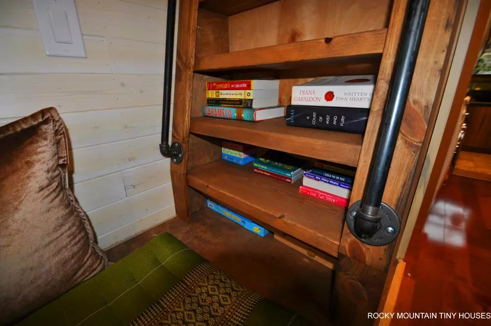 The secondary loft in the Red Mountain 34' Tiny House is the kid's bedroom and must be accessed by climbing a bookcase that doubles up as a ladder