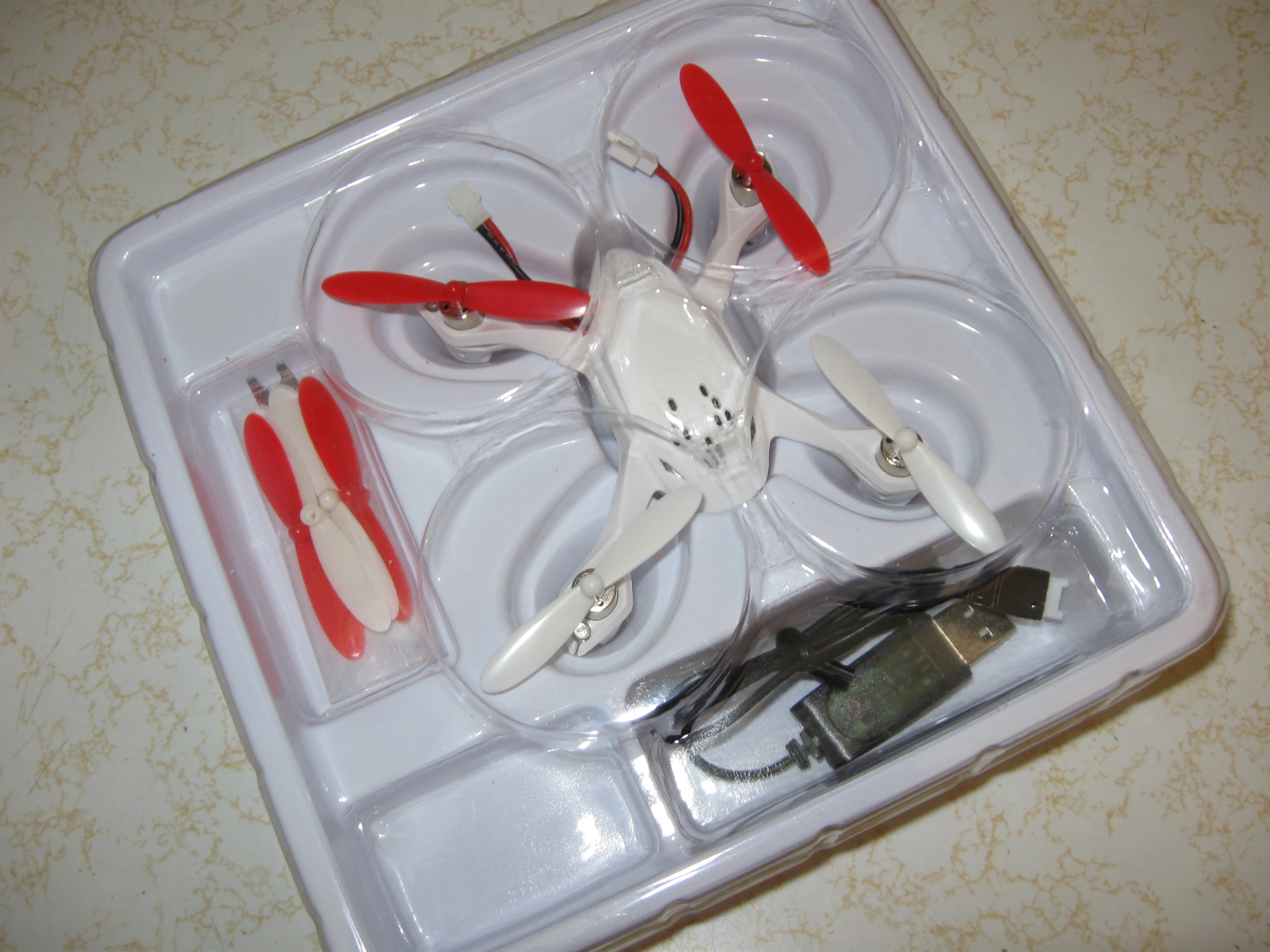 The FPV as it comes out of the box, with its charging cable and spare props