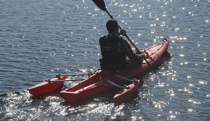 The outriggers are located towards the stern, where they shouldn't interfere with paddling