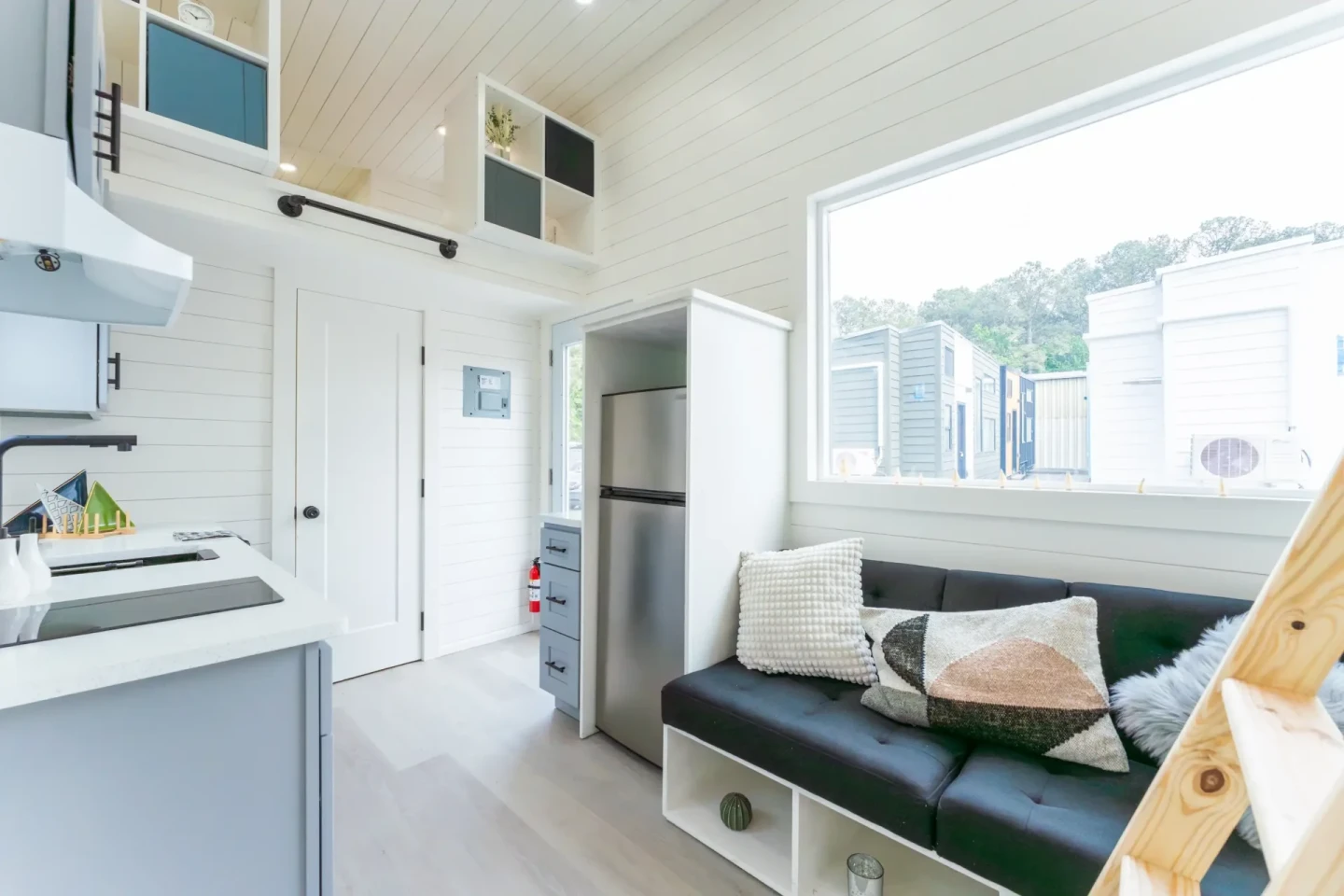 The Avalon 24' tiny house's living room is snug, but a large picture window helps fill the space with daylight