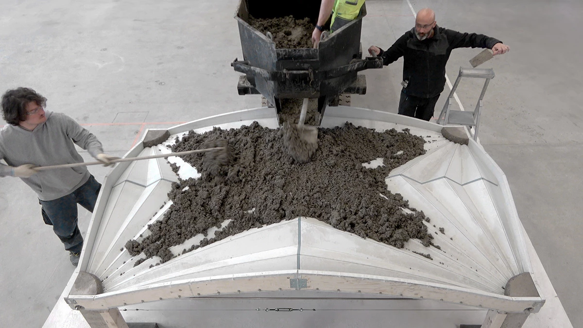Wet concrete mixture being poured into the Unfold Form framework to harden and set into a vaulted floor
