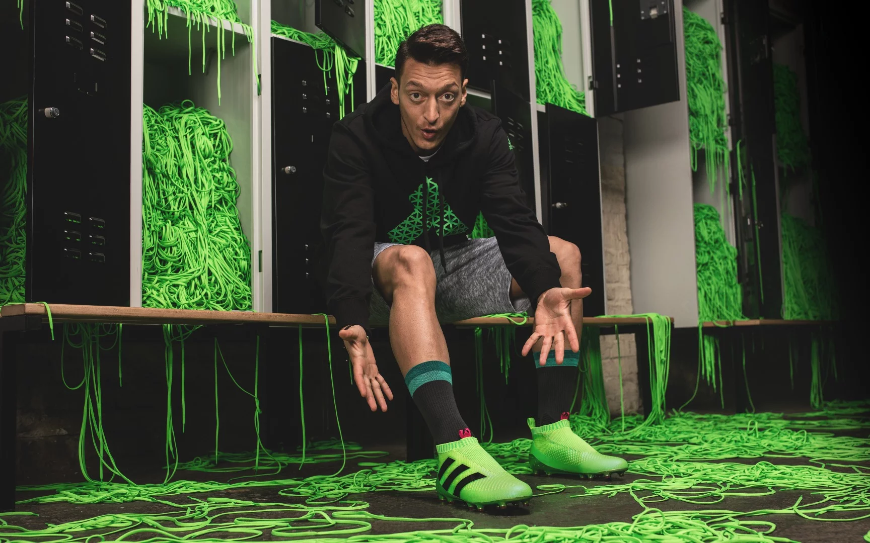 Arsenal's Mesut Ozil tries on a pair of Adidas' laceless football boots