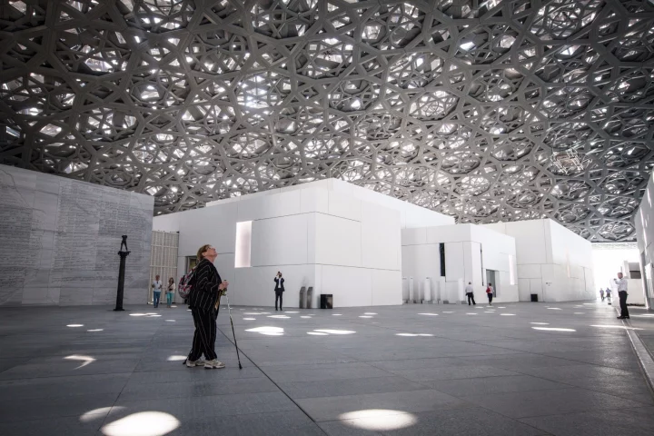 A visitor peers up towards the dome roofing at the Louvre Abu Dhabi