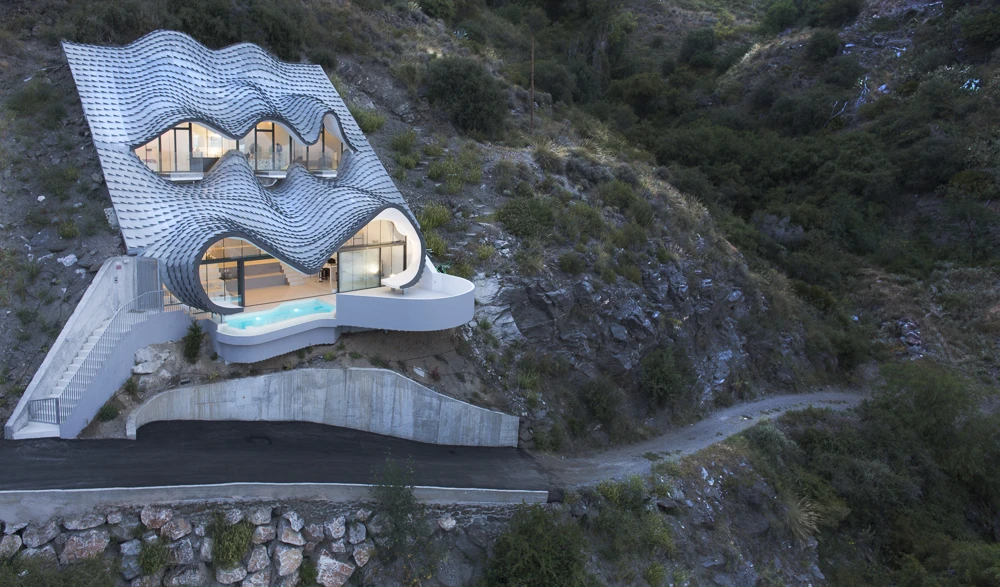 This incredibly impressive construction, designed by the GilBartolome studio, is buried into a hill on a plot with an inclination of 42 degrees. The undulous texture of the house is designed to resemble both the skin of a dragon and the waves of the ocean