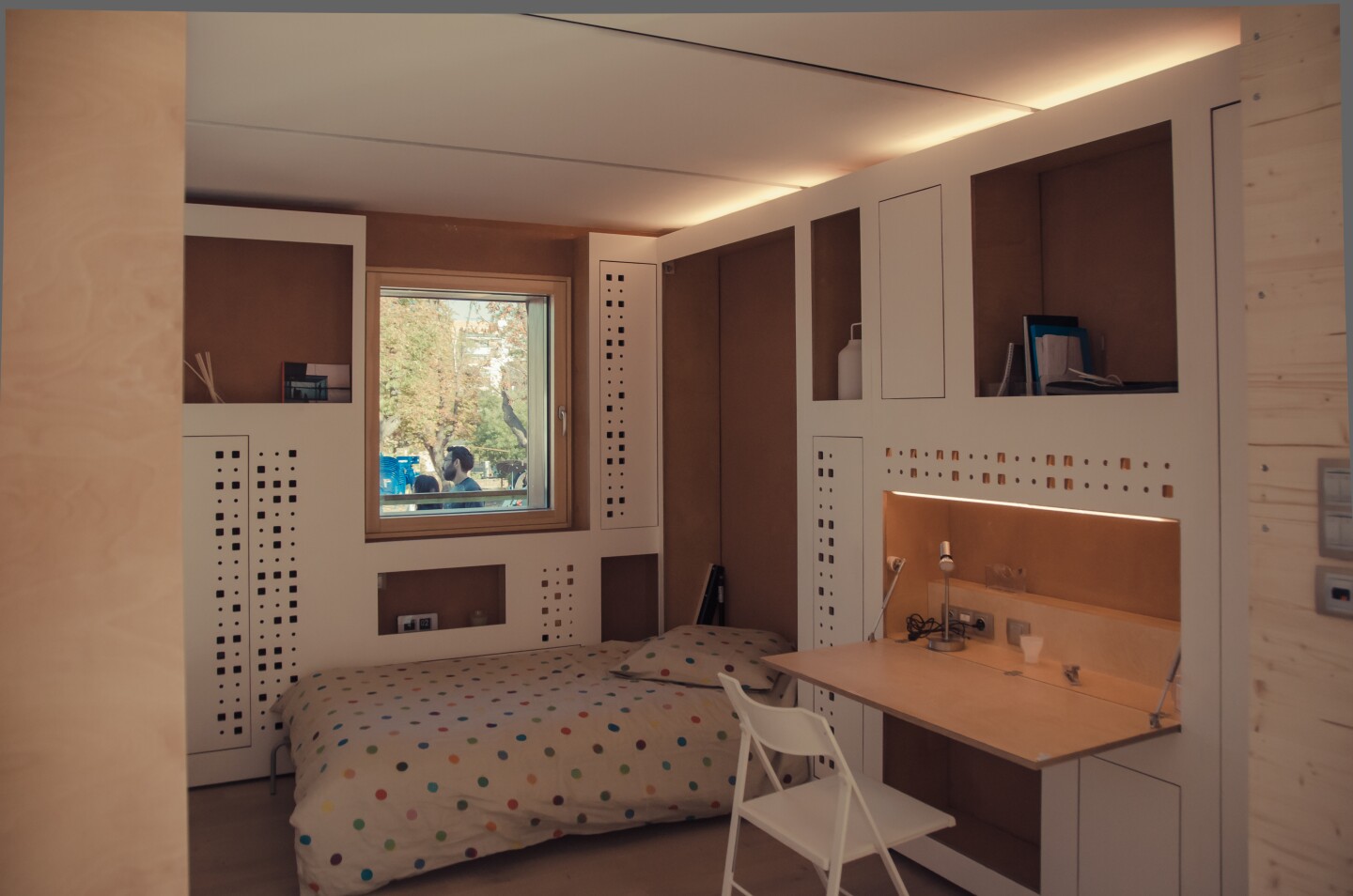 A storage wall cleverly disguises and stores a series of portable furniture elements that can be transformed into a bed, table or office
