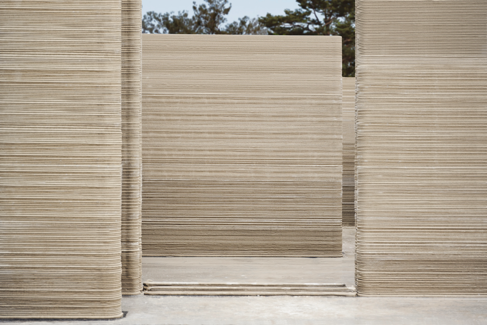 The 3D-printed home's walls were created by a robot extruding a cement-like mixture in layers, lending the walls a distinctive ribbed appearance