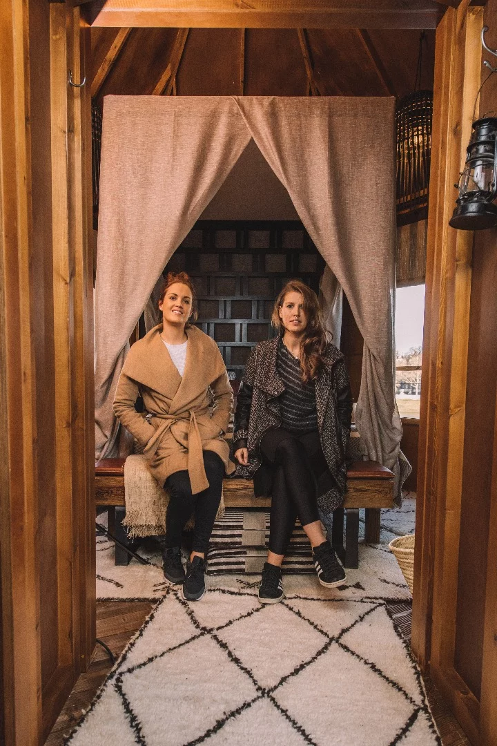 The interior features a four-poster bed and mosquito net, tribal prints, and assorted African sculpture and artwork