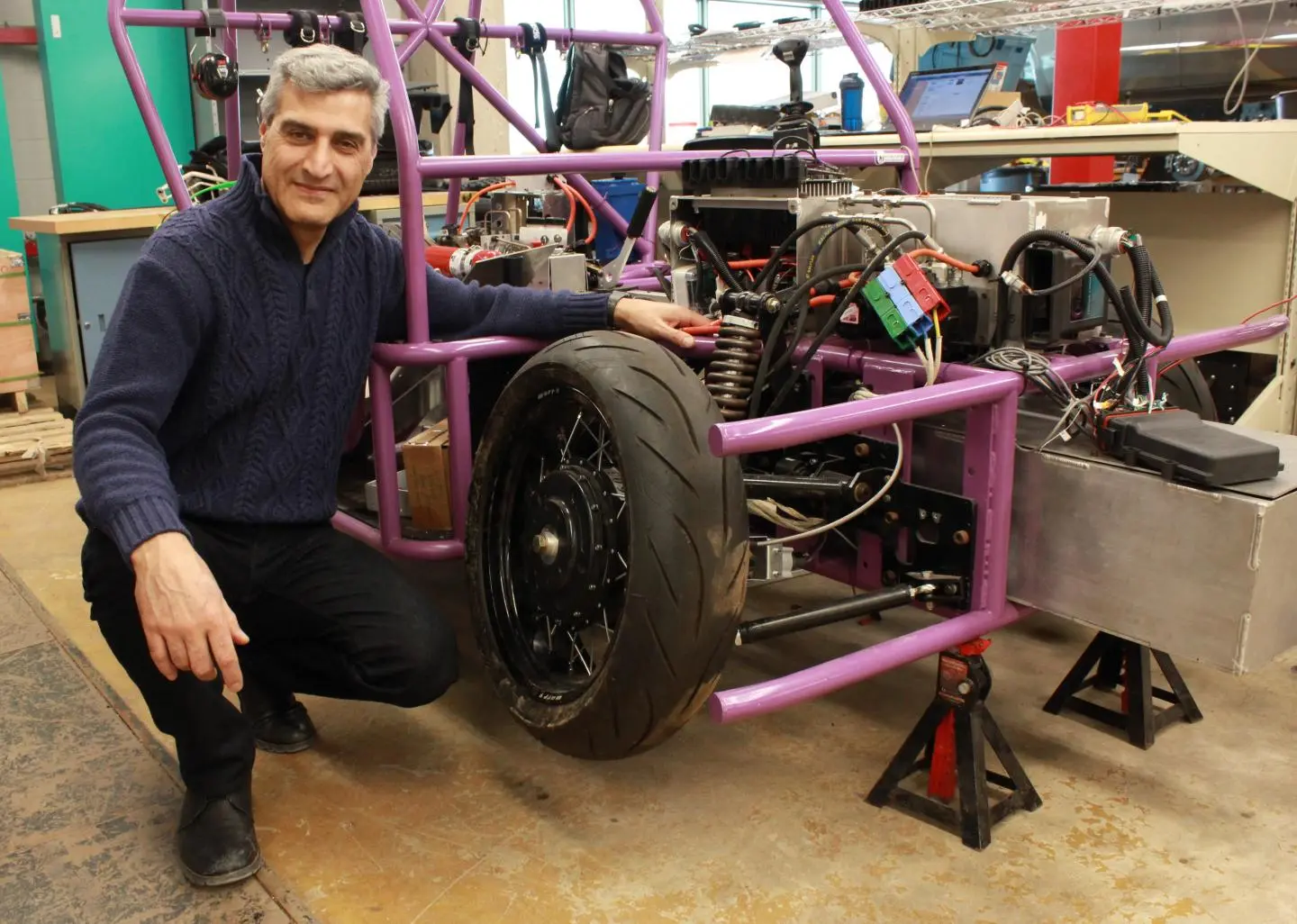 Prof. Amir Khajepour poses with a prototype three-wheeled vehicle that uses the new self-contained wheel units