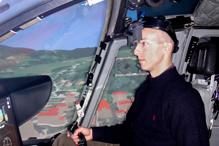 A pilot wearing the augmented reality system inside a helicopter flight simulator
