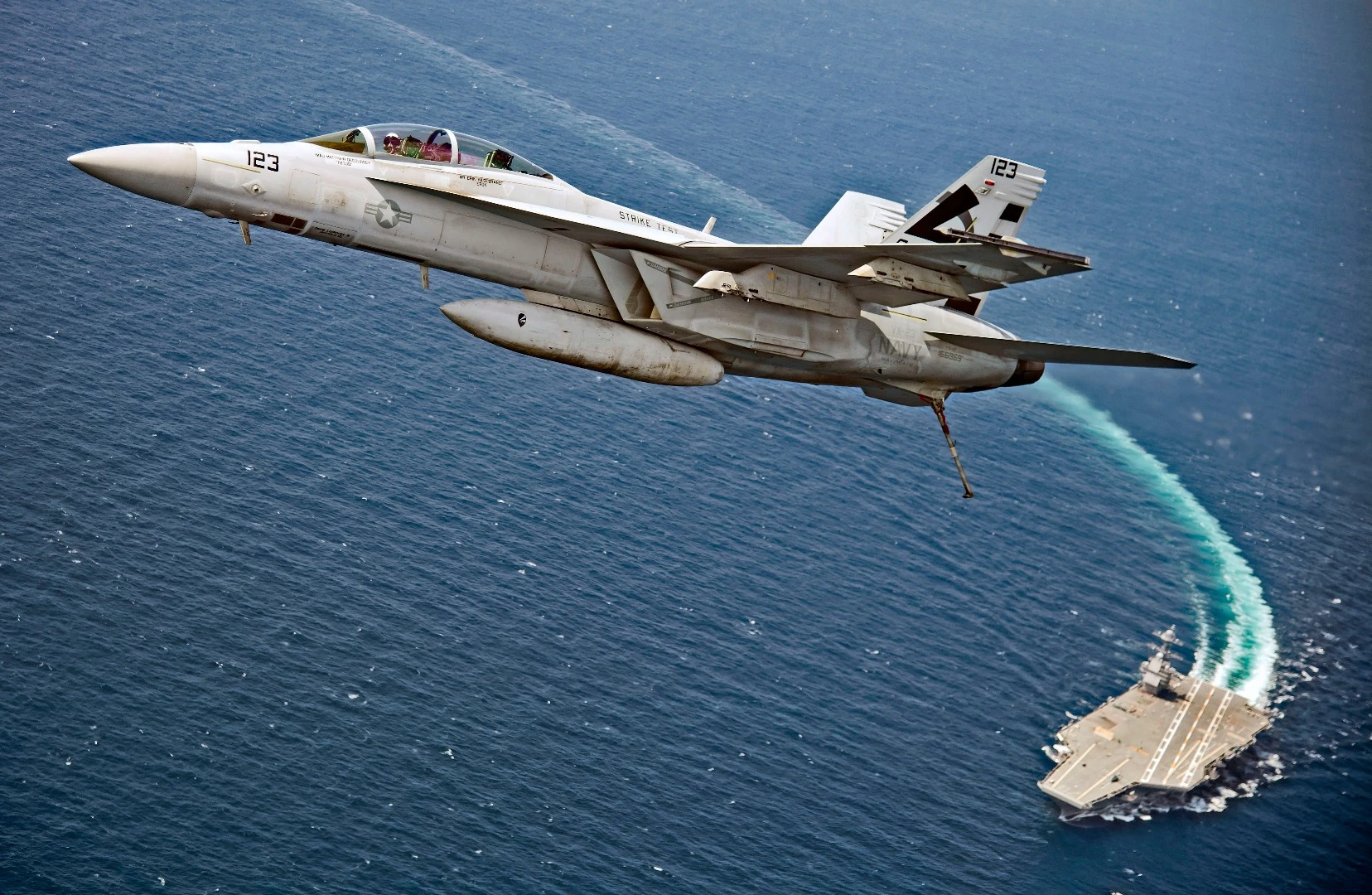 An F/A-18F Super Hornet assigned to Air Test and Evaluation Squadron (VX) 23 flies over USS Gerald R. Ford (CVN 78)