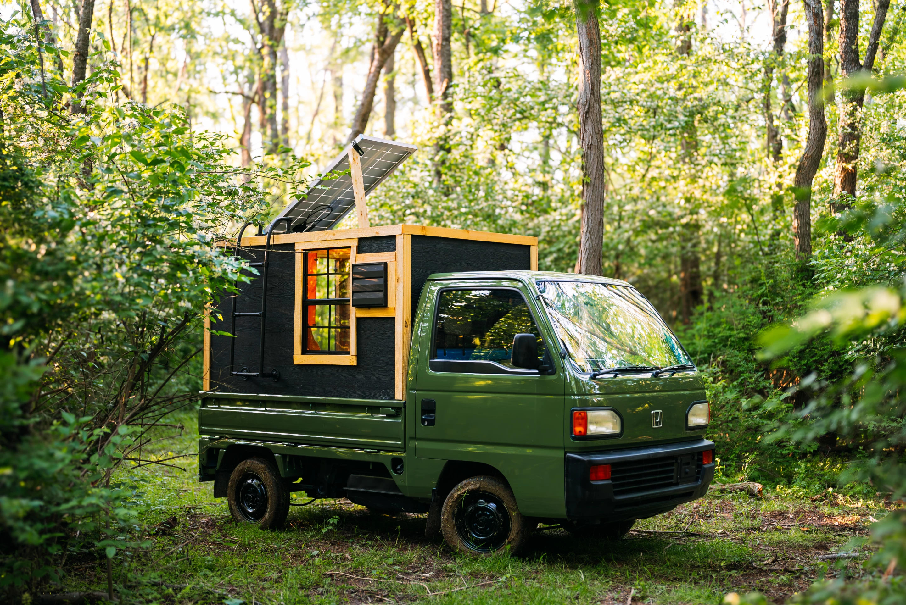 The micro-camper features a small solar panel on its roof, which can be adjusted by climbing up to the roof via a ladder