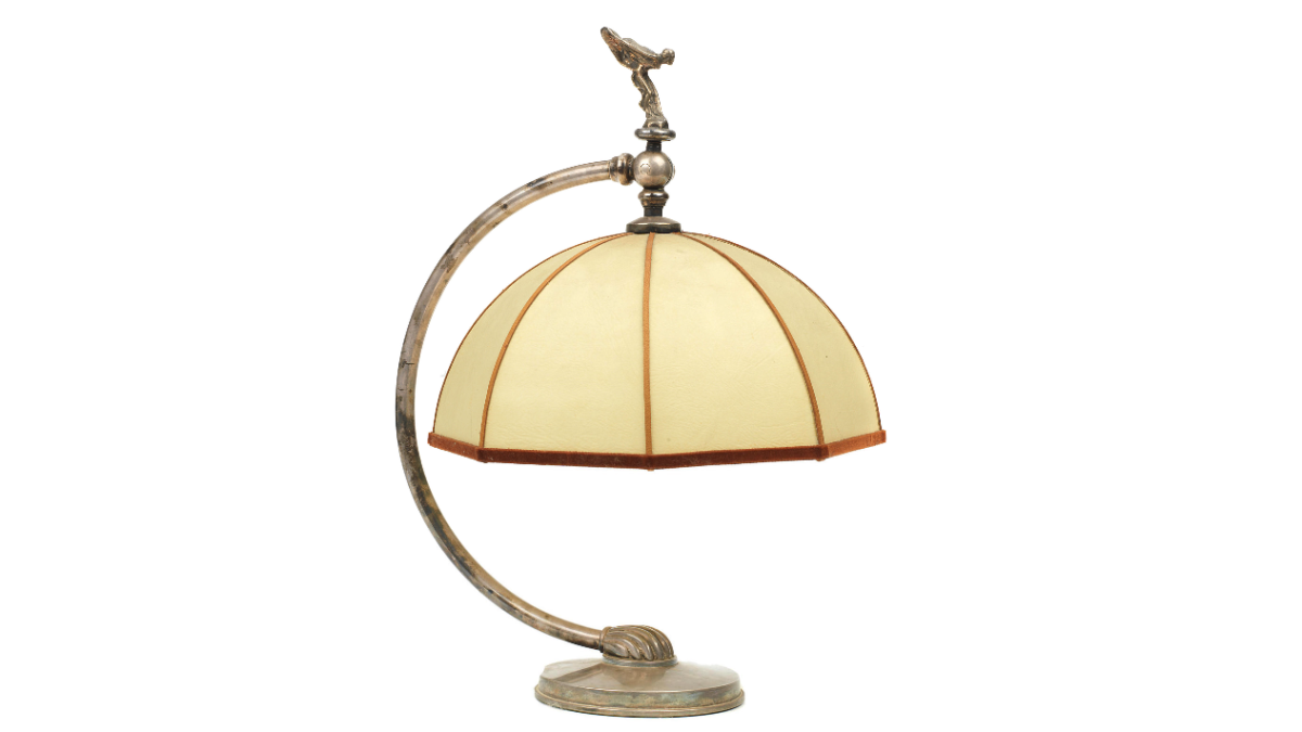Auction Link: Bonhams | Estimate: €900 to €1,200 | A replica Rolls-Royce table lamp after an original design by Charles Sykes, believed to have been made as a Christmas present in 1938. Plated lamp stand with curved stem surmounted by miniature 'Spirit of Ecstasy' mascot, with octagonal movable shade, 40.5 cm high