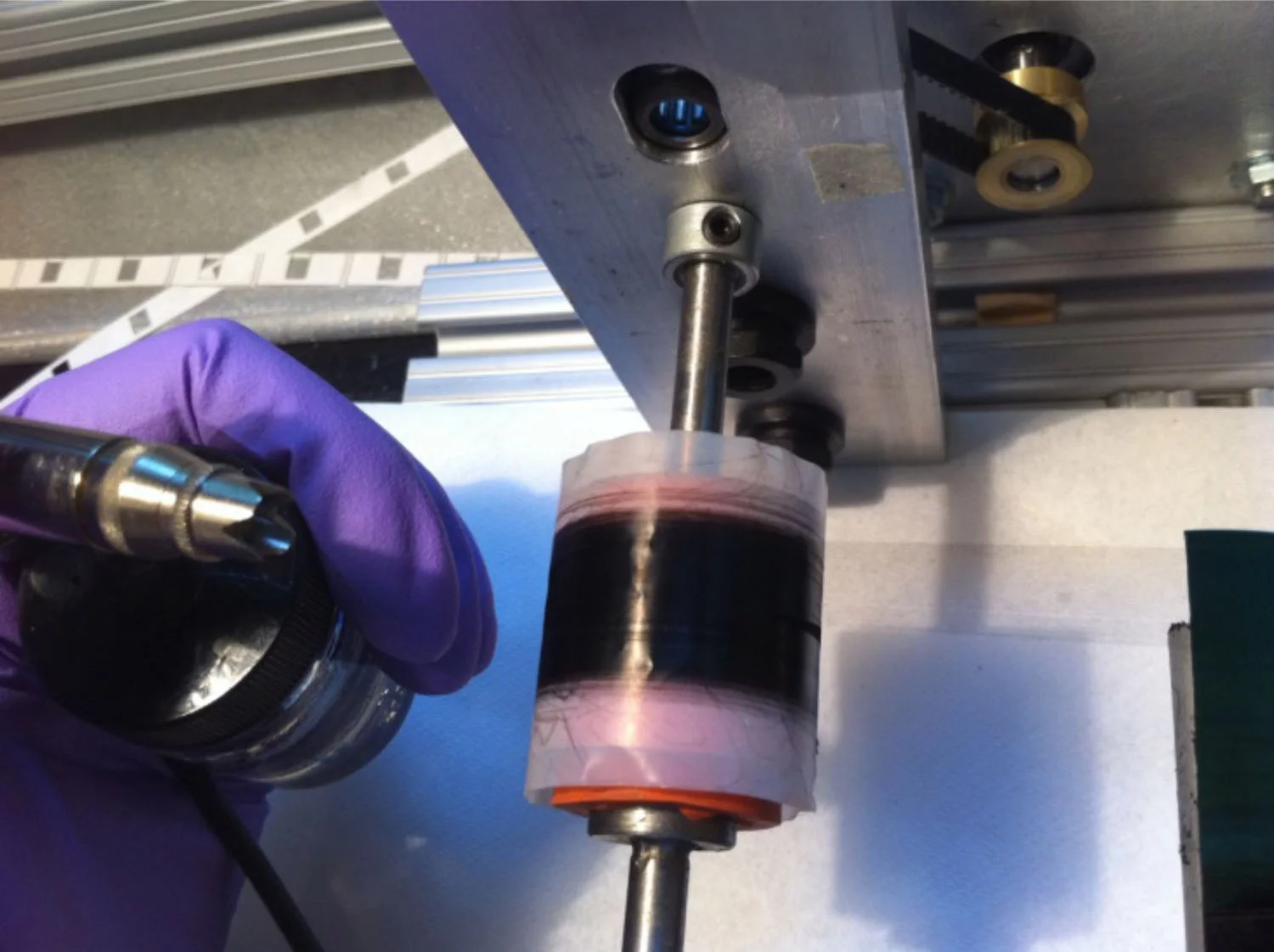 The ribbon-like material being wound onto a spool, while being sprayed with polymer and stretched